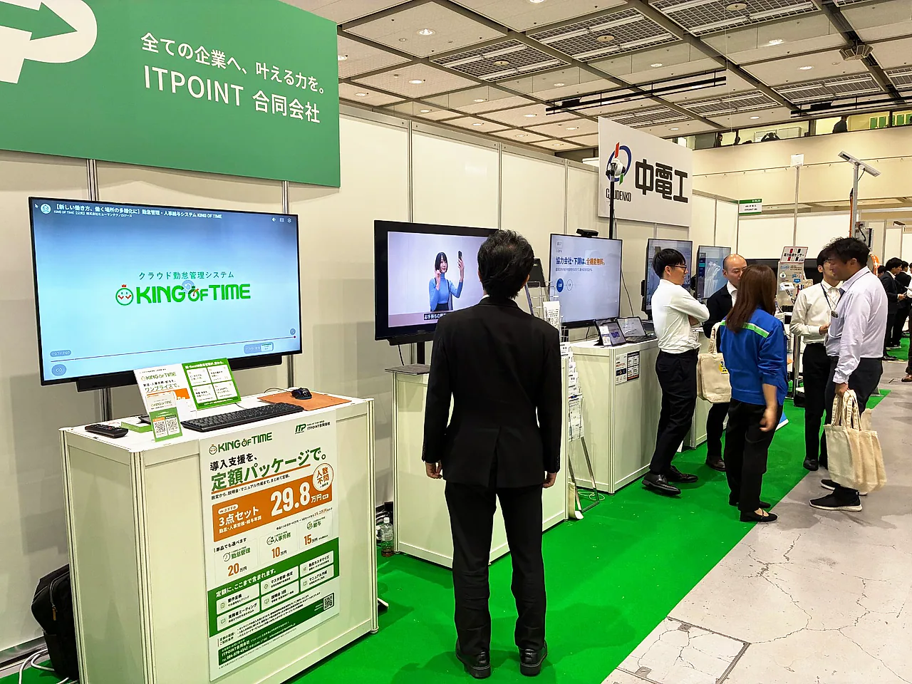 ITPOINTブースの様子。KING OF TIMEの導入支援パッケージのポスターとモニターが並び、その奥に中電工様のブースが見える