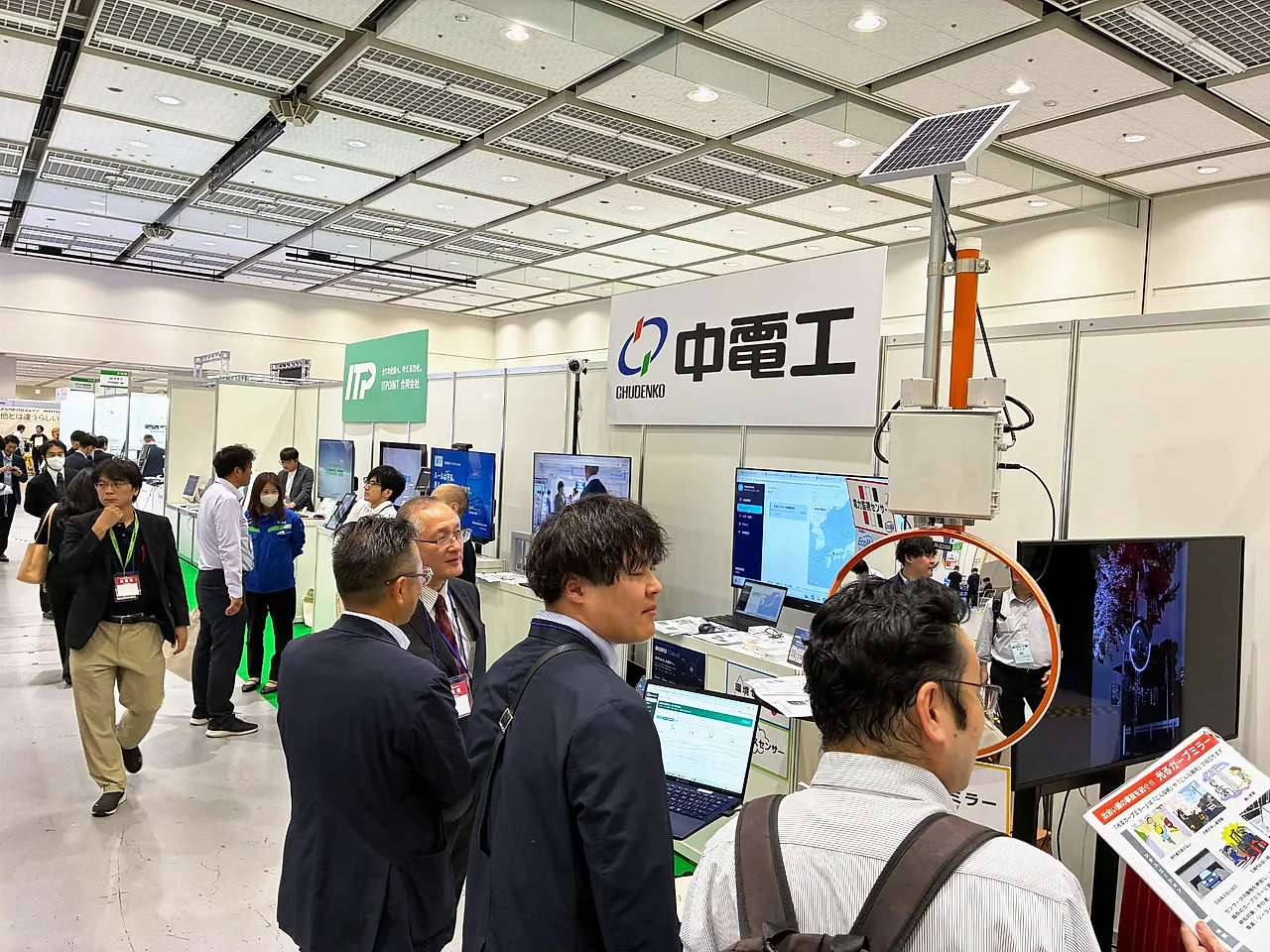 中電工様のブースの前で、多くの来場者がセンサーやモニターを見ている
